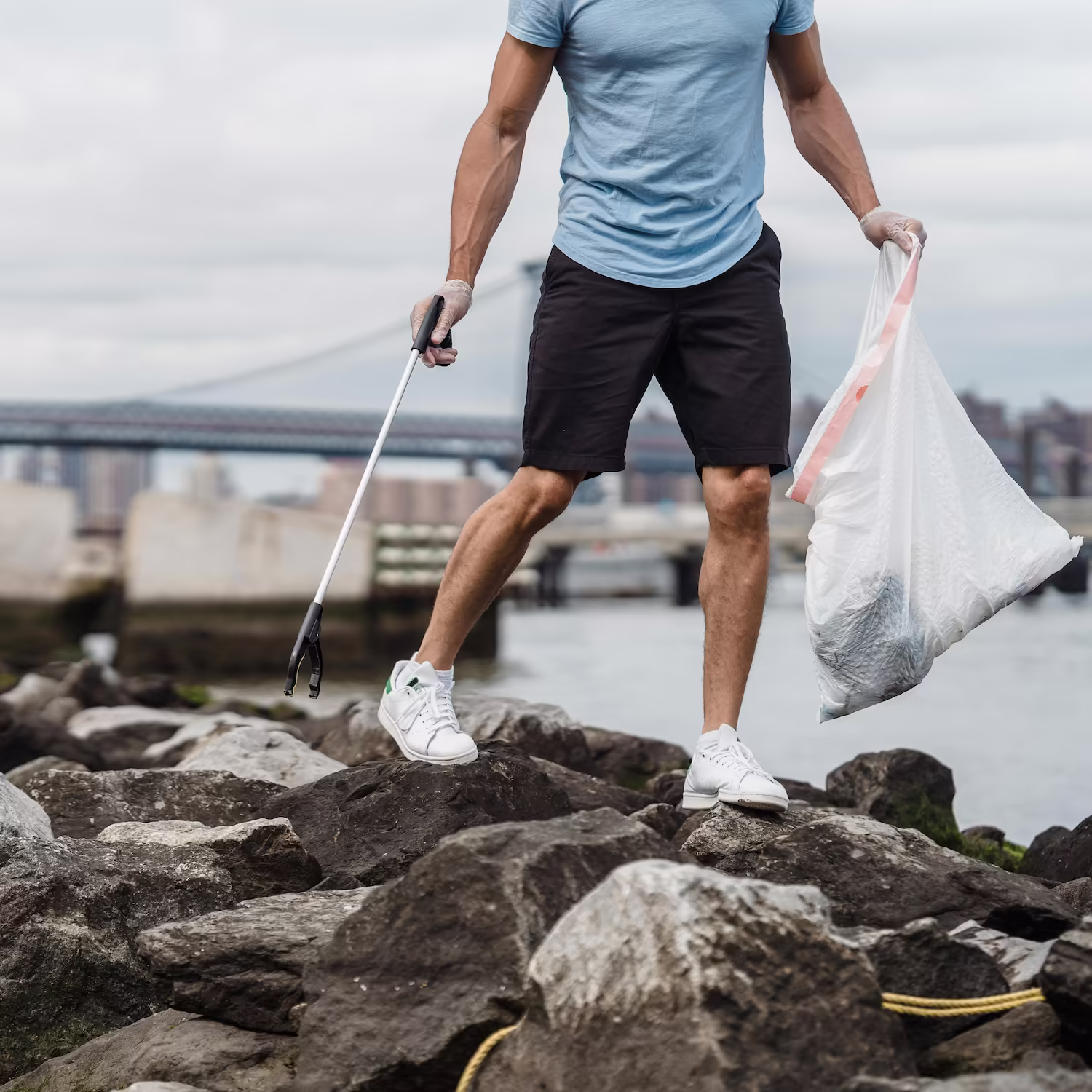 A person picking up litter on some rocks